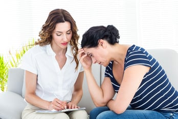 Depressed woman talking with her therapist on white background
