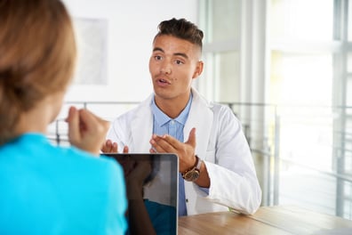 Team of doctor and nurse discussing a patient diagnosis sitting at the desk in bright modern office